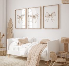 a white bedroom with three framed pictures on the wall