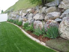 a large rock wall next to a green lawn