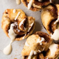 several pastries with icing on them sitting on a piece of parchmented paper