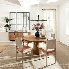 a dining room table with four chairs and a vase on top of it in front of a window