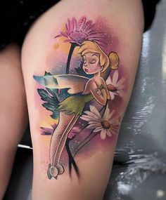 a woman's thigh with a flower and tinkerbell tattoo on it