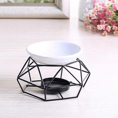 a white bowl sitting on top of a table next to a vase filled with flowers