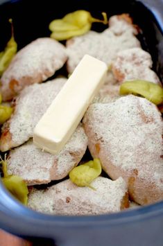 a blue bowl filled with food covered in powdered sugar and green peppers on top of a wooden table