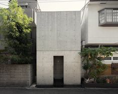 an apartment building with a concrete wall and door in the middle of it's side yard