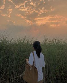 a woman standing in tall grass looking at the sky