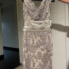 a dress hanging on a hanger in front of a door with a person's hand holding it up