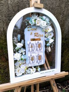 a wooden easel with flowers on it sitting in front of a wall