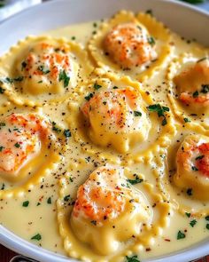 a white bowl filled with ravioli and cheese covered in scallops, garnished with parsley