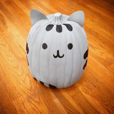 a white cat pumpkin sitting on top of a wooden floor