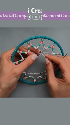 two hands are working on a beaded project with beads and wire in the middle