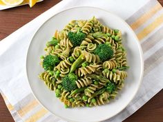 a white plate topped with pasta and broccoli on top of a wooden table