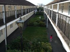 an apartment complex with two balconies and a small child walking in the yard