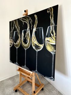 an easel with three wine glasses on it and one is painted in black, yellow and white