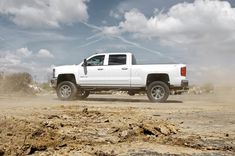 a white truck driving down a dirt road in the middle of some rocks and dirt