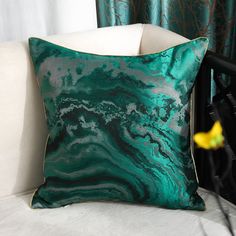 a green and white pillow sitting on top of a couch next to a yellow flower