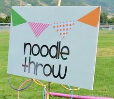 a sign that says noodle throw in front of a field with hula hoopes