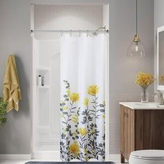 a shower curtain with yellow flowers on it in a bathroom next to a toilet and sink