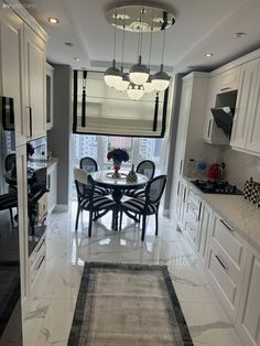 a dining room and kitchen area with white cabinets, marble flooring and chandelier