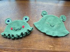 two knitted hats sitting on top of a wooden table