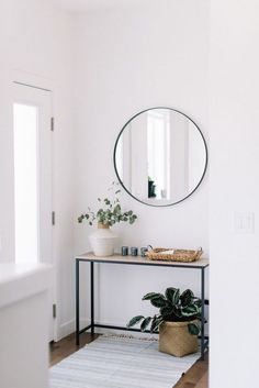 a white room with a mirror, potted plant and rug