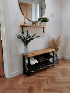 a wooden bench sitting next to a mirror on top of a wall near a plant