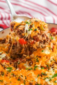 a spoon full of cheese and meat casserole being lifted with a spatula