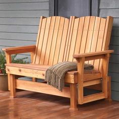 a wooden bench sitting on top of a hard wood floor next to a potted plant