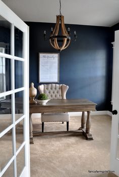 a living room with a chandelier and table in the middle, blue walls