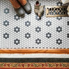 two pairs of shoes sitting on top of a tiled floor next to a shower stall