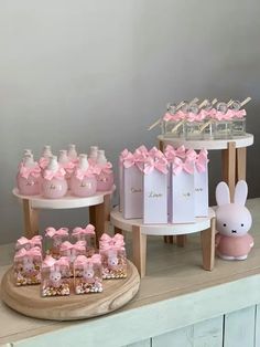 pink and white baby shower items displayed on wooden stand with bunny decorations in front of them