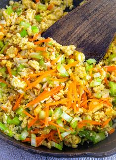 a wooden spoon in a bowl filled with rice and vegetables