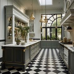 a kitchen with black and white checkered flooring, gold accents and hanging lights