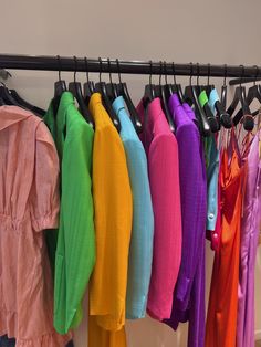 there are many different colored shirts hanging on the rack