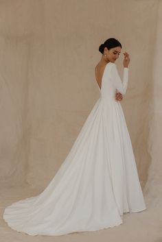 a woman in a white wedding dress posing for the camera with her hand on her head