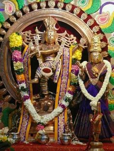 an idol is displayed in front of a decorated wall with flowers and garlands on it