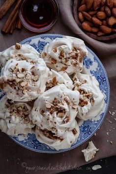 a blue and white plate topped with whipped cream covered desserts next to almonds