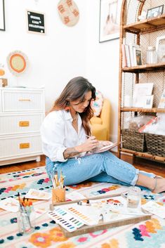 a woman sitting on the floor working on her craft project