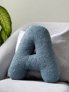 a blue stuffed animal sitting on top of a white couch next to a green plant