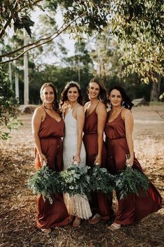 the bridesmaids are all dressed in maroon dresses and holding greenery wreaths