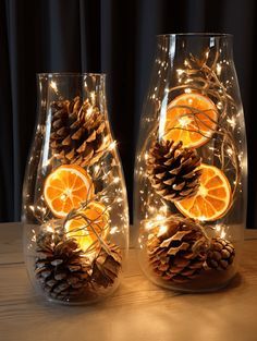 two clear glass vases with orange slices and pine cones on the inside, surrounded by string lights