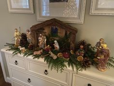 a white dresser topped with christmas decorations and figurines on top of it's drawers