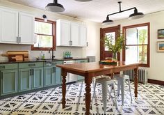 a kitchen with green cabinets and black and white flooring, along with an island in the middle