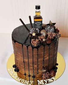 a birthday cake with chocolate frosting and candies on the top is decorated with an assortment of liquor bottles