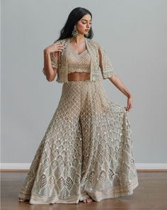 Beige flared palazzo pants paired with a matching blouse and cropped cape jacket, with sequined embroidery all over. DELIVERY TIMEPlease allow 1 week for your outfit to be dispatched. FABRIC DETAILSNet Professional cleaning only. Glamorous Festive Embroidered Sets, Bollywood Style Cape Sets For Party, Bollywood Style Party Sets With Cape, Glamorous Festive Set With Cape Sleeves, Glamorous Festive Sets With Cape Sleeves, Festive Party Palazzo Set With Cape, Glamorous Embroidered Festive Sets, Chic Embroidered Festive Sets, Elegant Palazzo Set With Cape For Festive Occasions