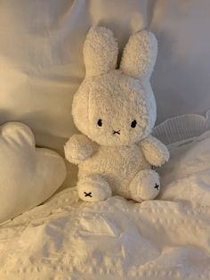 a white stuffed rabbit sitting on top of a bed