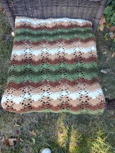 a crocheted blanket sitting on top of a wicker chair in the grass