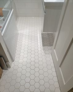 a bathroom with white tile and hexagonal pattern on the floor