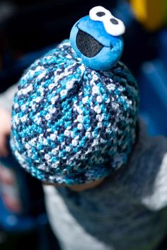 a close up of a person wearing a knitted hat with a cookie monster on it