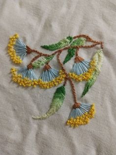 a close up of a piece of cloth with embroidered flowers on it and green leaves