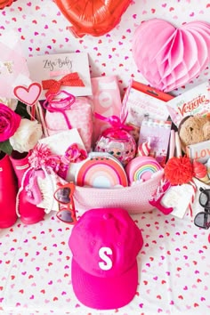 a pink hat and other items on a white tablecloth with hearts, balloons and paper